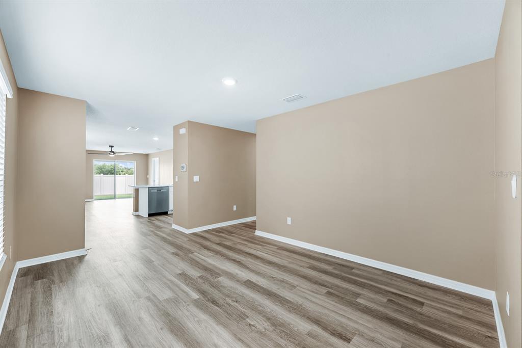 A dining room with a wooden table, chairs, and a sideboard on wood-look flooring — 5029 ROCKY COAST PLACE, PALMETTO, FL