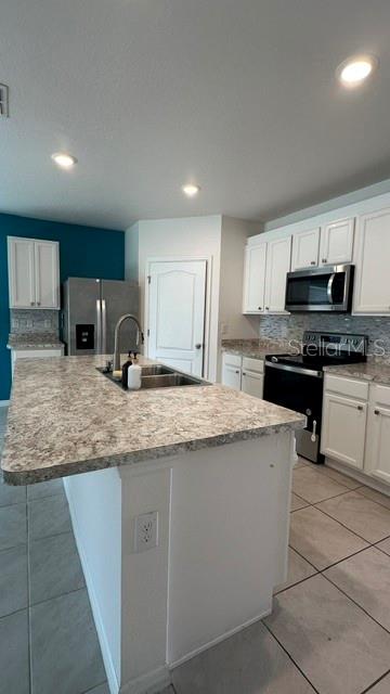 A kitchen with white cabinets, a large island with a sink, and stainless steel appliances — 494 JACKS WAY, DAVENPORT, FL