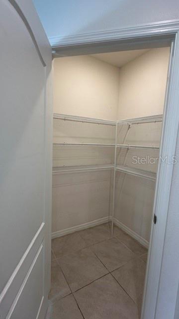 A walk-in pantry features white wire shelving and light-colored tile flooring — 494 JACKS WAY, DAVENPORT, FL