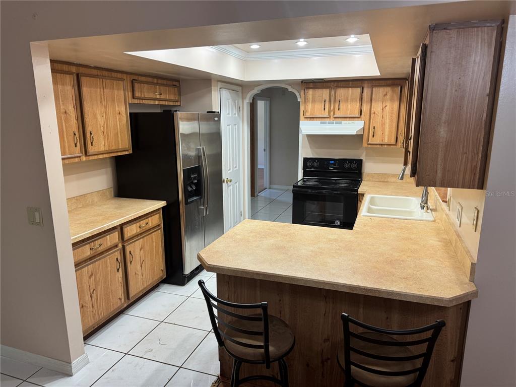 A kitchen features wood cabinets, laminate countertops, stainless steel appliances, and a breakfast bar — 1401 ASTER COURT, WINTER PARK, FL