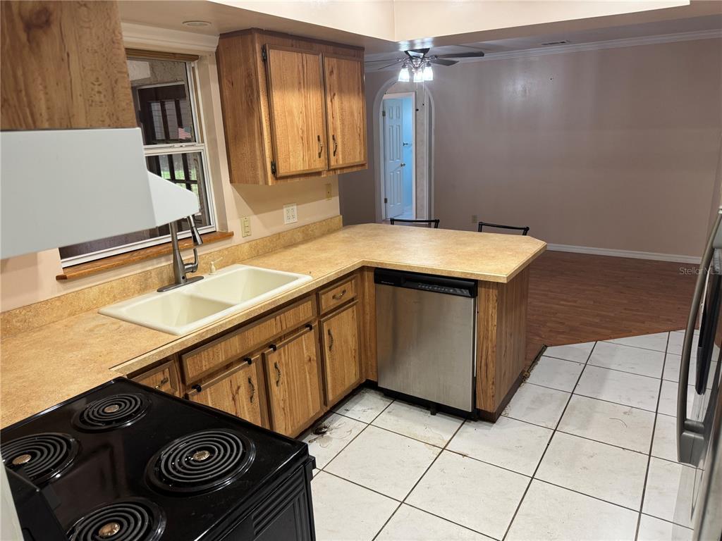 A kitchen features oak cabinets, tan laminate countertops, a white sink, and white tile flooring — 1401 ASTER COURT, WINTER PARK, FL