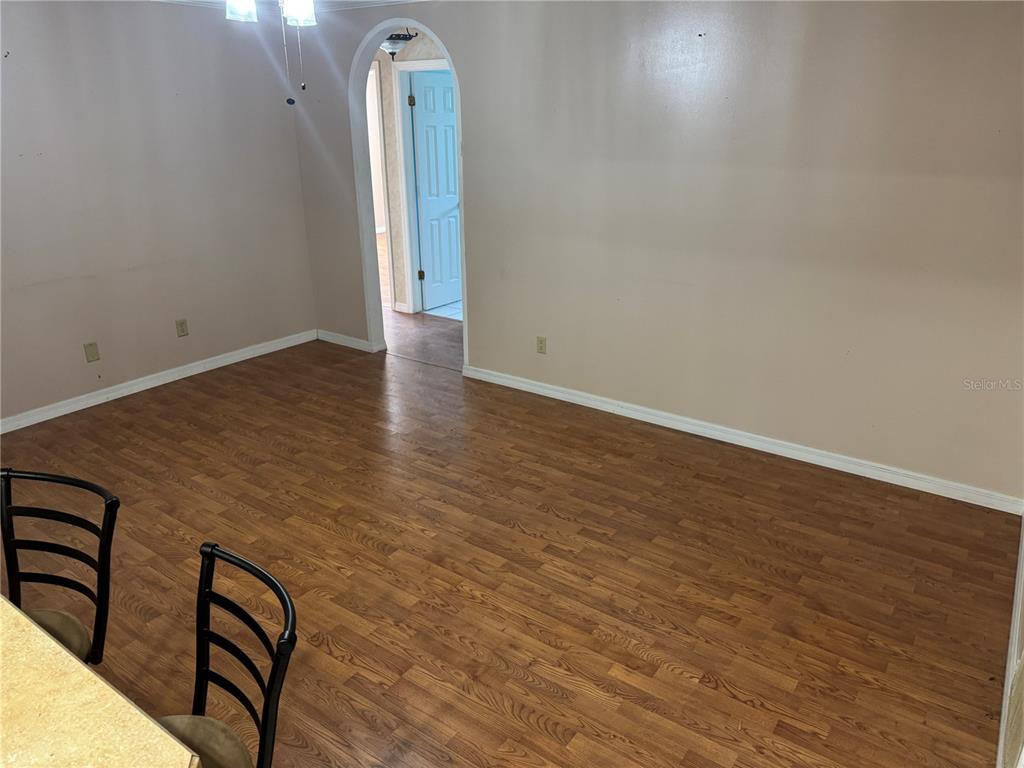 An empty dining area features wood-look laminate flooring, beige walls, and an arched doorway — 1401 ASTER COURT, WINTER PARK, FL