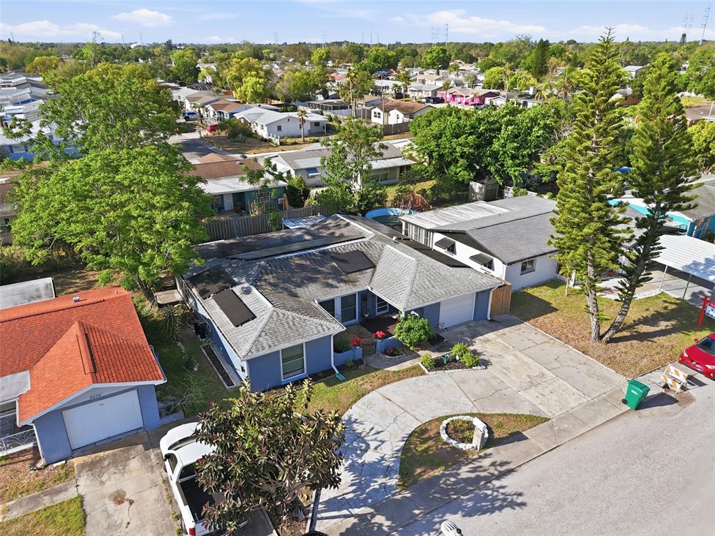 An aerial view shows a blue house with a gray roof and solar panels — 3226 FAIRMOUNT DRIVE, HOLIDAY, FL