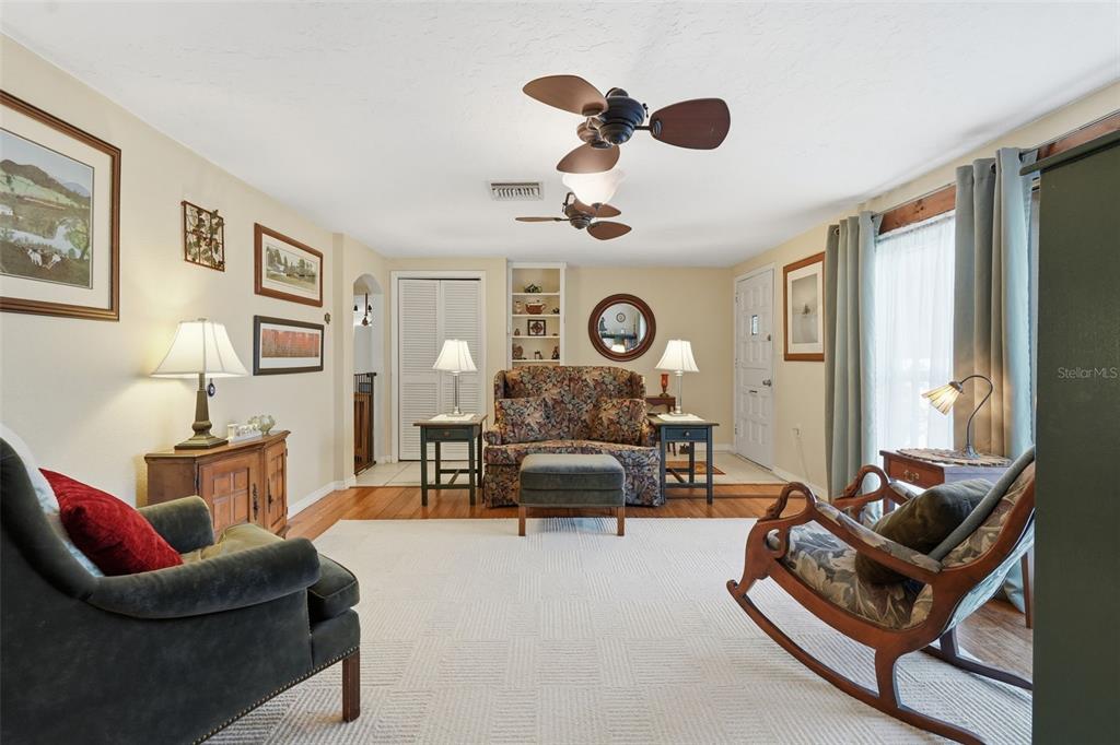 A living room features a patterned sofa, a rocking chair, and a large white rug — 3226 FAIRMOUNT DRIVE, HOLIDAY, FL