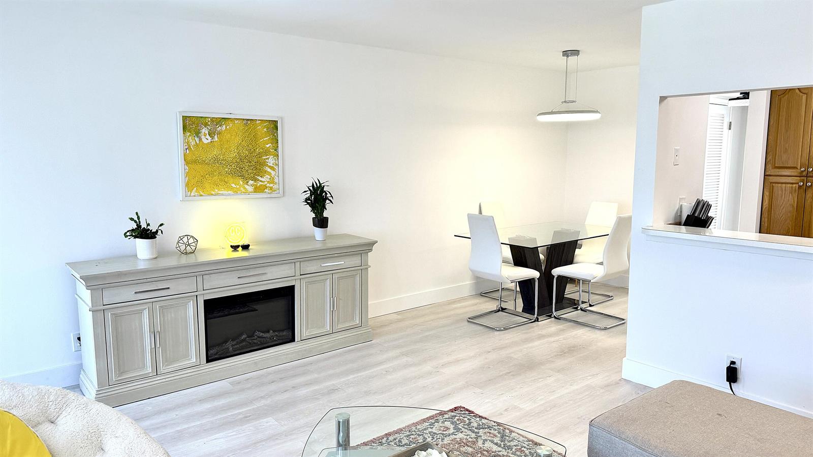 A dining area and living room feature a fireplace console, glass table, and white walls — 78 Harwood H Crescent, Deerfield Beach FL 33442, DEERFIELD BEACH, FL