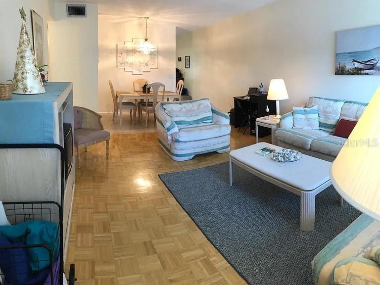 A living room and dining area featuring a sofa, recliner, and a round dining table — 2071 AUSTRALIA WAY W UNIT 29, CLEARWATER, FL