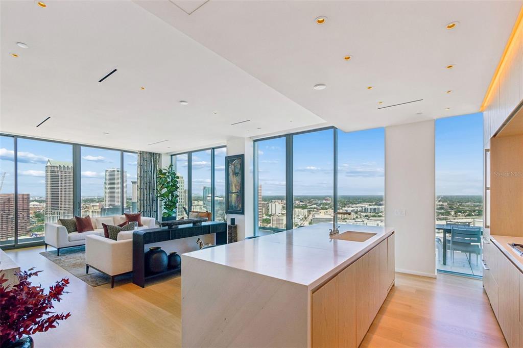 A modern open-concept kitchen and living area with floor-to-ceiling windows overlooking a city skyline — 1000 WATER STREET UNIT 2501, TAMPA, FL