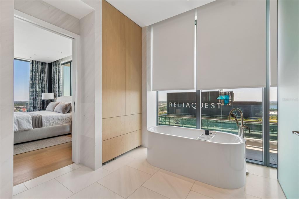 A modern bathroom features a freestanding tub, light wood cabinetry, and floor-to-ceiling windows — 1000 WATER STREET UNIT 2501, TAMPA, FL