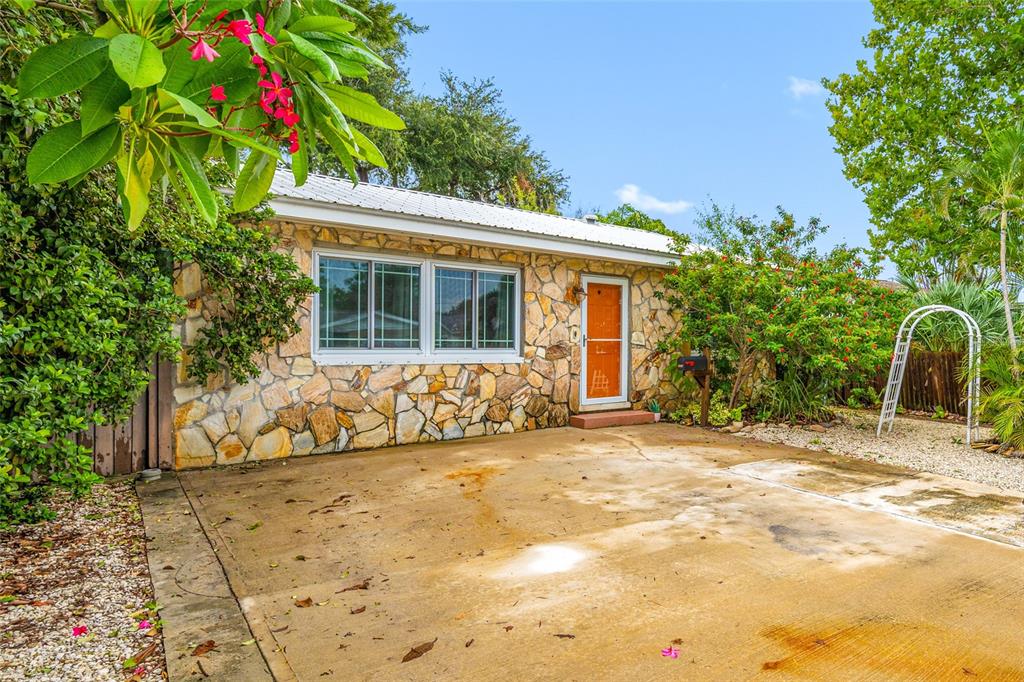 A single-story house with a stone facade, white metal roof, and a concrete driveway — 3935 11TH AVENUE N, ST PETERSBURG, FL