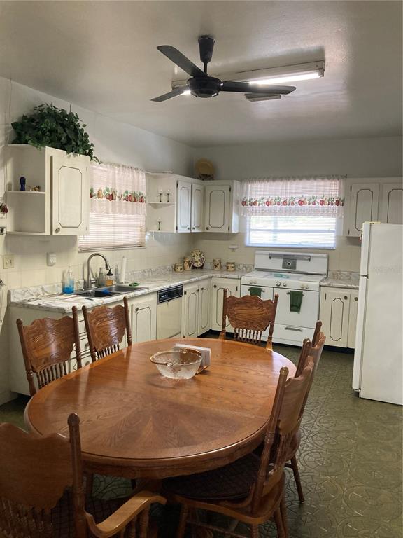 A kitchen with white cabinets, a wooden dining table, and green patterned flooring — 2405 CORRINE STREET, TAMPA, FL