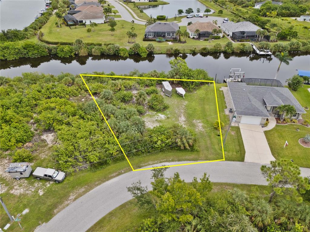 An aerial view shows a vacant, trapezoidal residential lot bordered by a canal and road — 8050 SANTA CRUZ DRIVE, PORT CHARLOTTE, FL