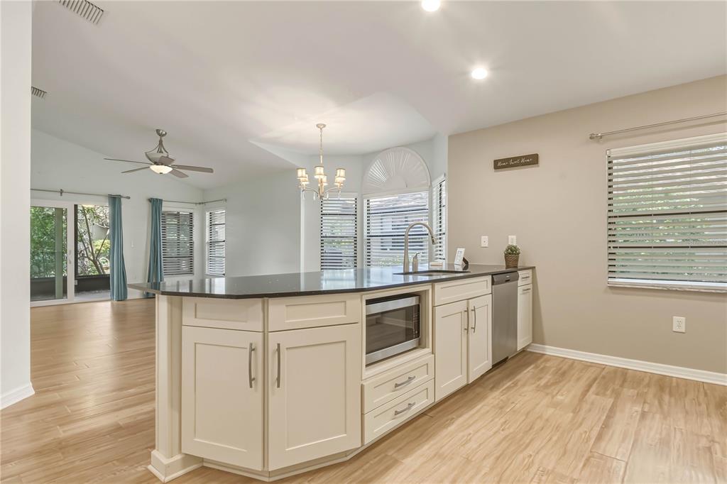 A kitchen island with a built-in microwave sits in an open-concept room with light flooring — 1696 NASH COURT, DUNEDIN, FL