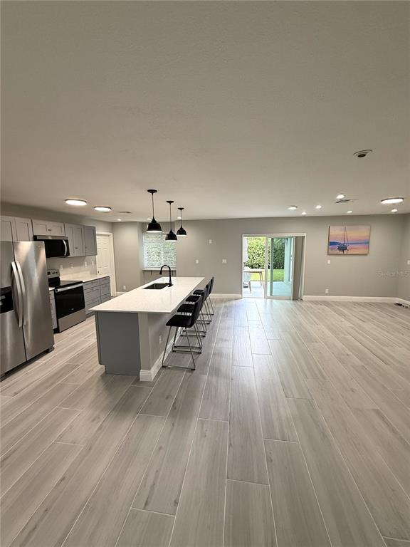 A modern kitchen with a large island, stainless steel appliances, and light wood-look tile flooring — 12480 SW 2ND STREET, PLANTATION, FL