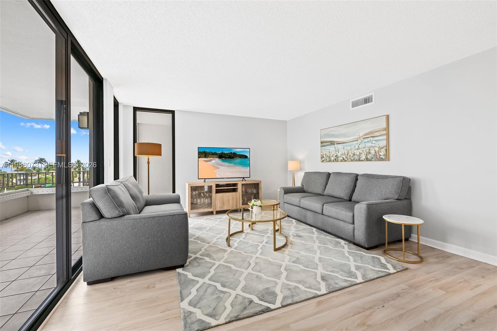 A living room features gray sofas, a patterned rug, and a balcony with outdoor views — 1401 S Ocean Blvd # 407, Pompano Beach FL 33062, POMPANO BEACH, FL