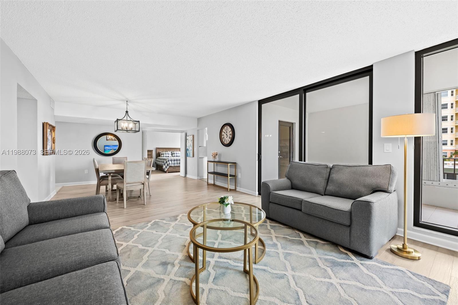 A living and dining area features gray sofas, a glass coffee table, and wood-look flooring — 1401 S Ocean Blvd # 407, Pompano Beach FL 33062, POMPANO BEACH, FL