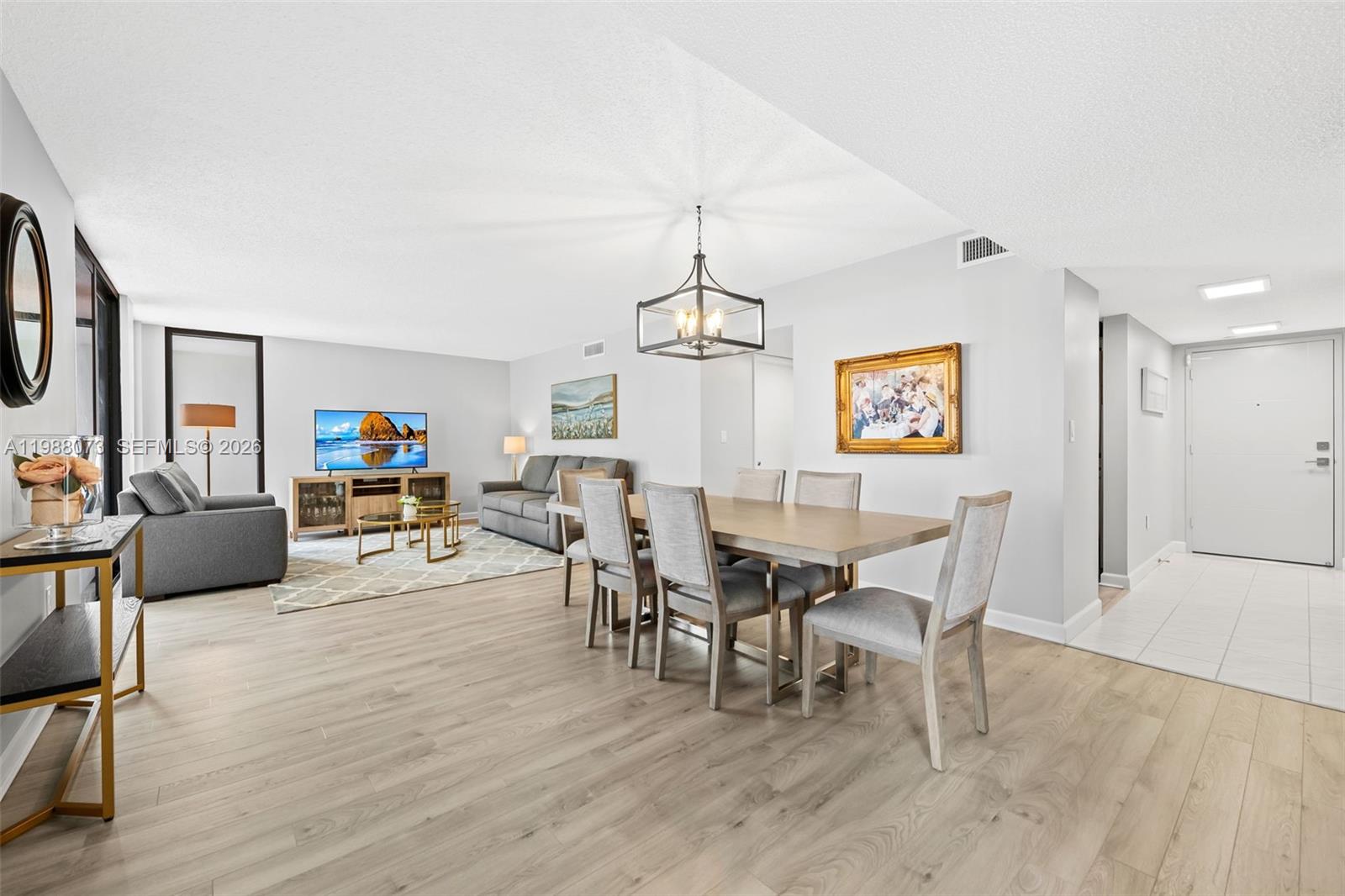 This open-concept living and dining area features light wood flooring and a modern chandelier — 1401 S Ocean Blvd # 407, Pompano Beach FL 33062, POMPANO BEACH, FL