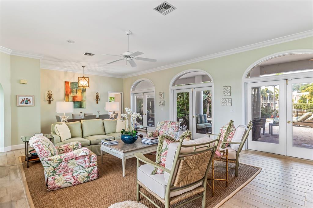 A living room features a light green sofa, floral armchairs, and glass doors leading outside — 252 WATERWAYS AVENUE, BOCA GRANDE, FL