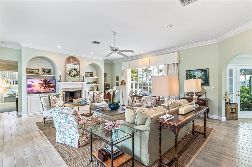A living room features a fireplace, built-in shelving, a ceiling fan, and light-colored tile flooring — 252 WATERWAYS AVENUE, BOCA GRANDE, FL