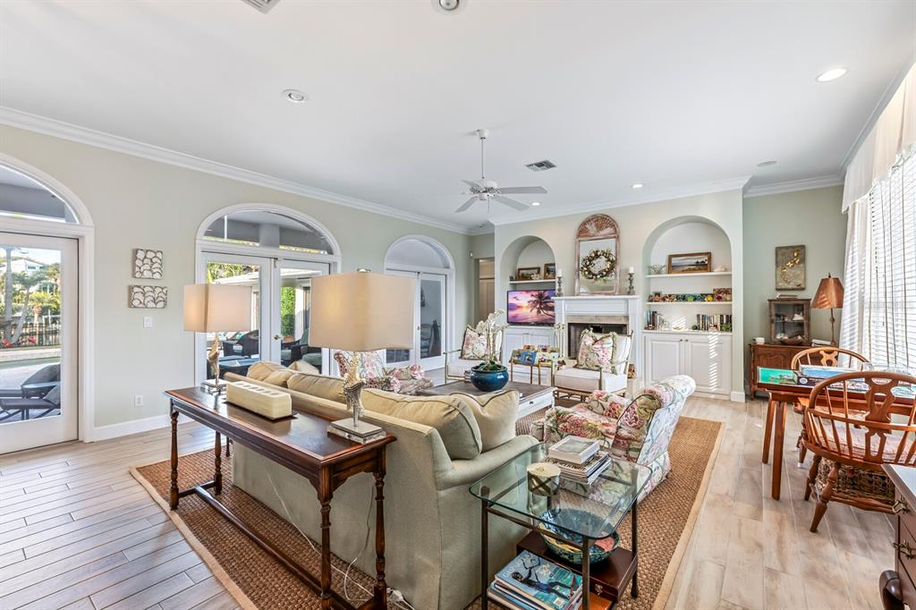 A living room features a fireplace, built-in shelving, a sofa, and glass doors to a patio — 252 WATERWAYS AVENUE, BOCA GRANDE, FL