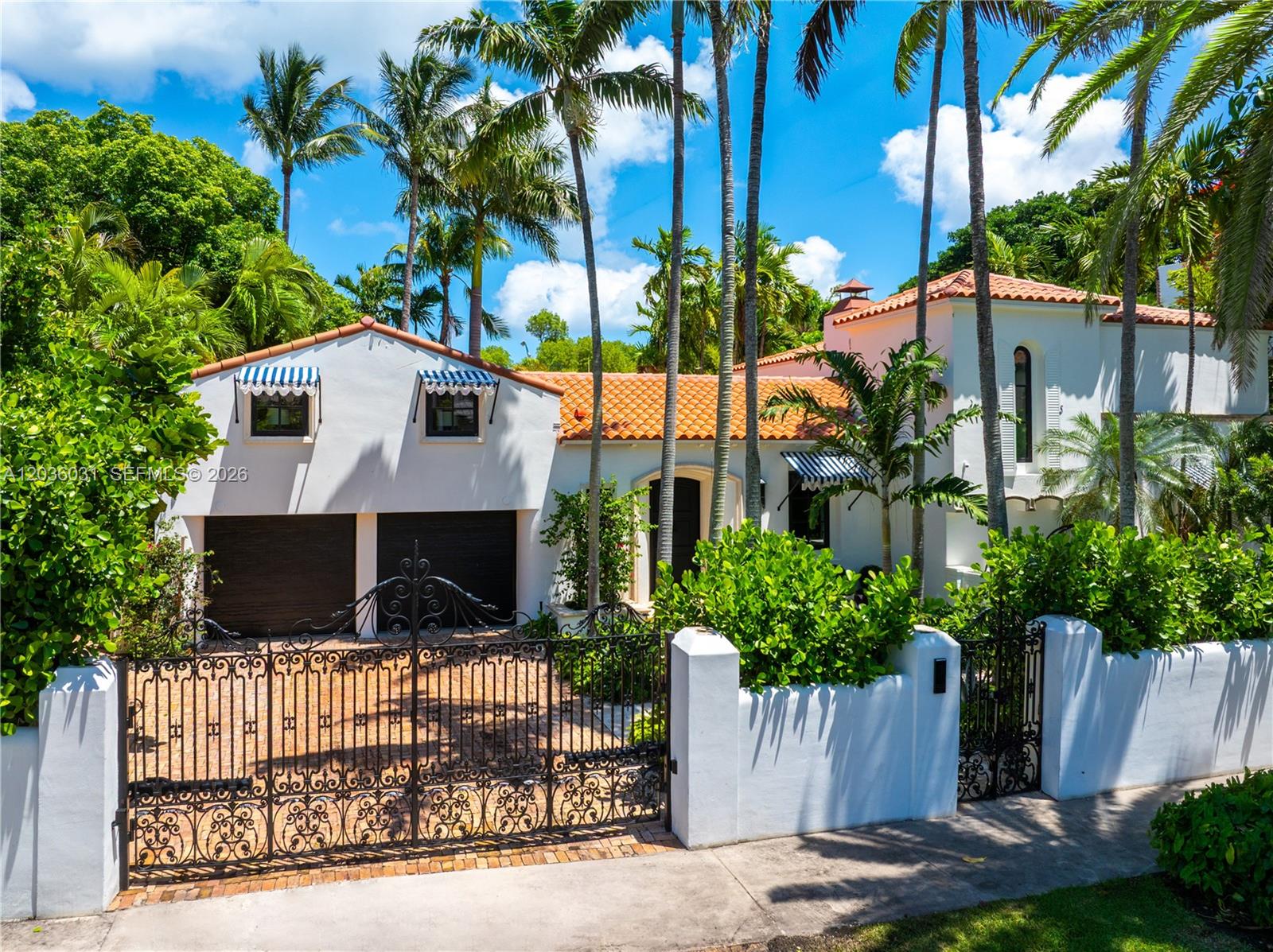 A white stucco house with a tiled roof, gated driveway, and palm trees in the yard — 4727 N Bay Rd, Miami Beach FL 33140, MIAMI BEACH, FL