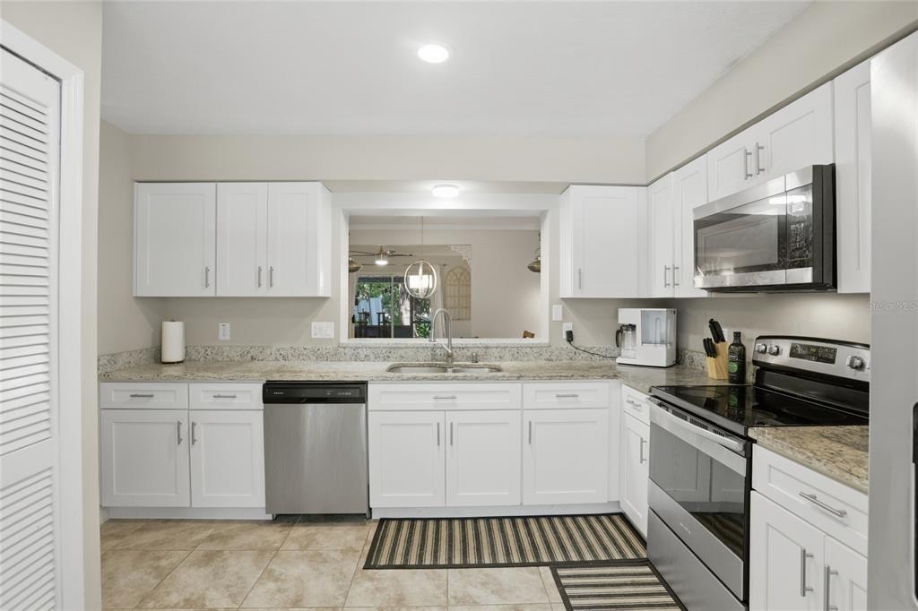 A kitchen with white cabinets, stainless steel appliances, granite countertops, and a pass-through window — 504 GREEN SPRING CIRCLE, WINTER SPRINGS, FL