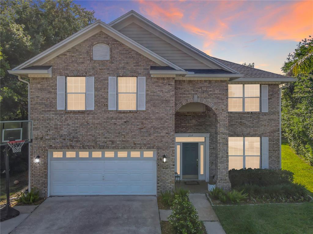 A two-story brick house with a two-car garage and an arched entryway at dusk — 237 CEDARWOOD COURT, DEBARY, FL
