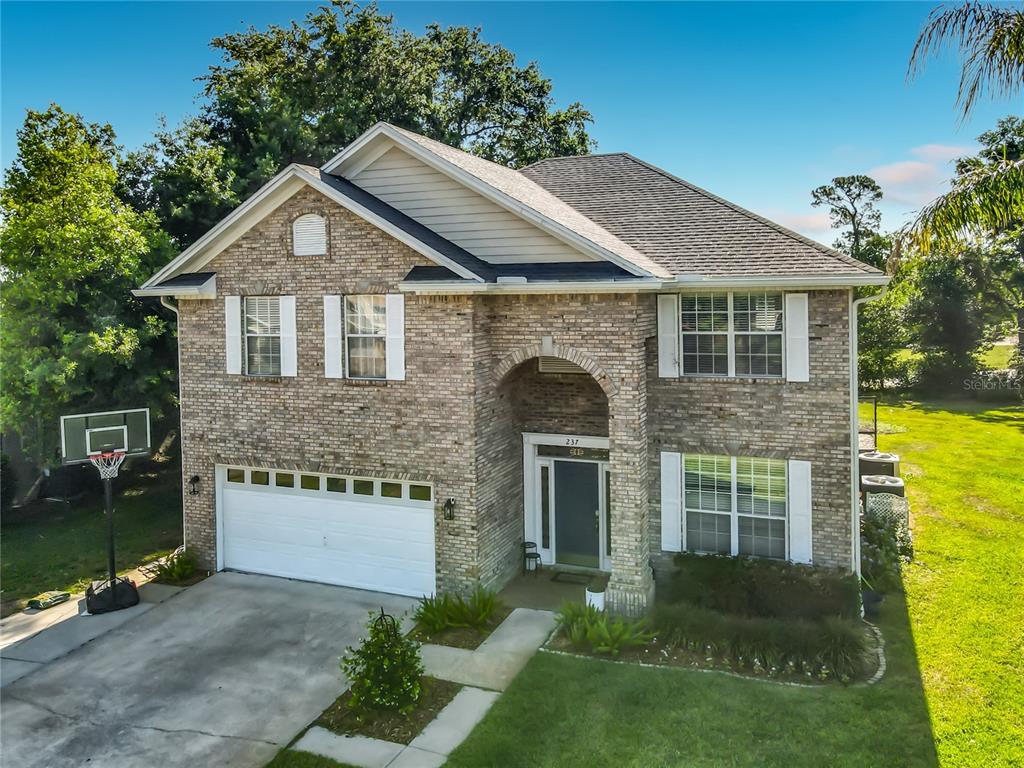 A two-story brick house features a two-car garage, a covered entryway, and a basketball hoop — 237 CEDARWOOD COURT, DEBARY, FL
