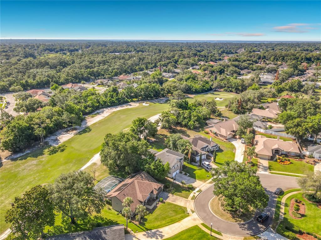 An aerial view shows houses situated along a golf course fairway surrounded by dense trees — 237 CEDARWOOD COURT, DEBARY, FL