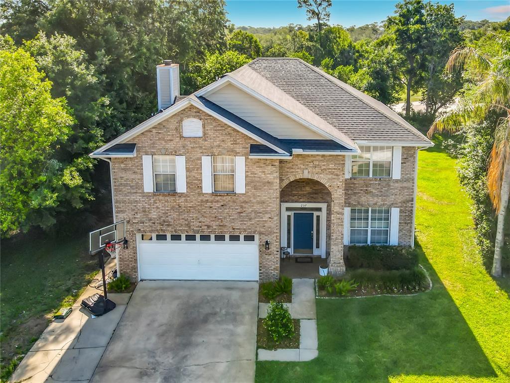 An aerial view of a two-story brick house with a white garage and front entrance — 237 CEDARWOOD COURT, DEBARY, FL