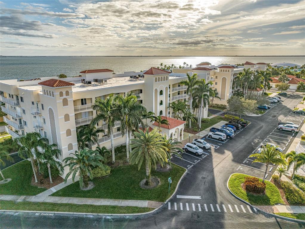An aerial view shows a multi-story apartment building with a tiled roof near the water — 551 CASA BELLA DRIVE UNIT 206, CAPE CANAVERAL, FL