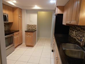 A kitchen features light wood cabinets, dark granite countertops, stainless steel appliances, and tiled floors — LAUDERHILL, FL