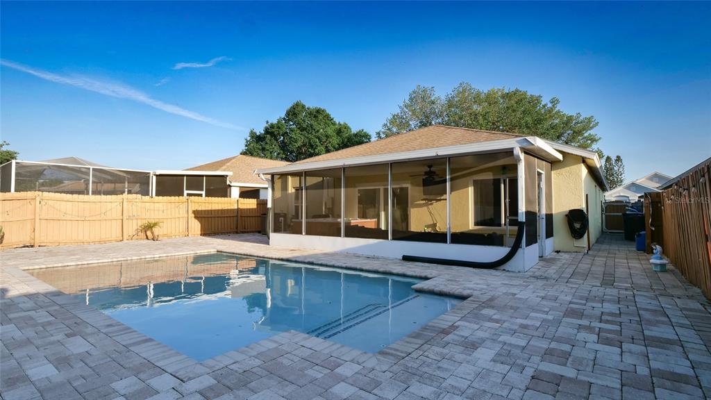 A backyard features a rectangular swimming pool, a screened-in patio, and a wooden privacy fence — 10510 EGRET HAVEN LANE, RIVERVIEW, FL