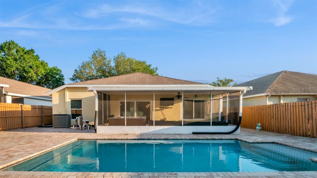 A backyard features a rectangular swimming pool, a screened-in patio, and wooden privacy fencing — 10510 EGRET HAVEN LANE, RIVERVIEW, FL