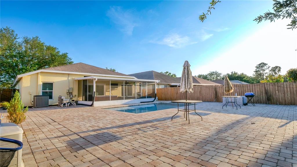 A backyard features a paved patio, a rectangular swimming pool, and a screened-in porch area — 10510 EGRET HAVEN LANE, RIVERVIEW, FL