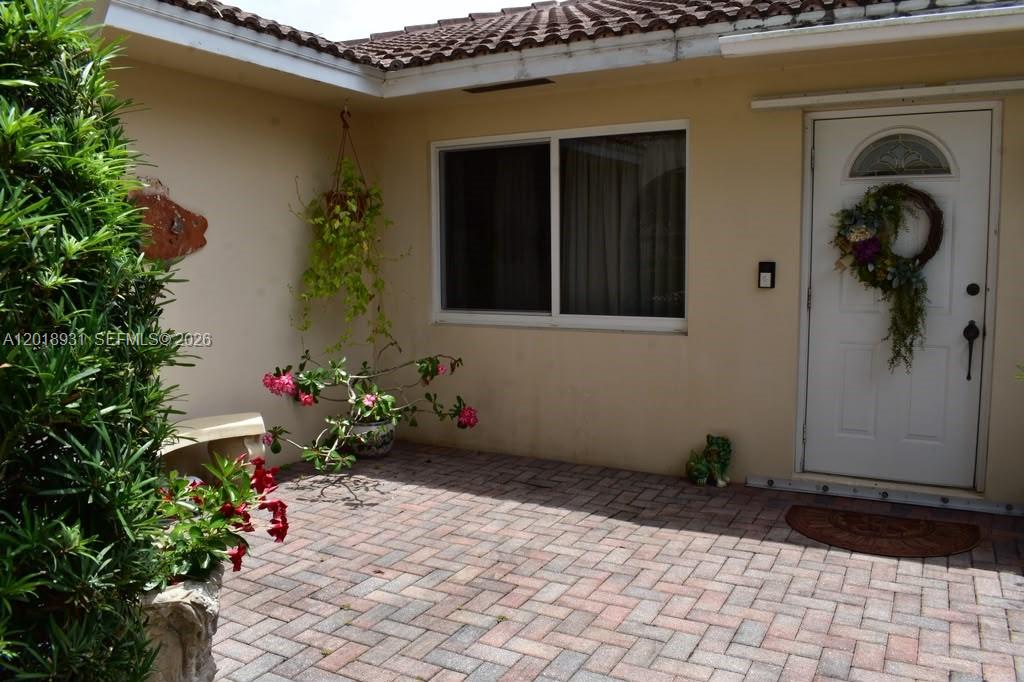 A paved patio area sits in front of a house with a white front door — 3634 Lowson Blvd, Delray Beach FL 33445, DELRAY BEACH, FL