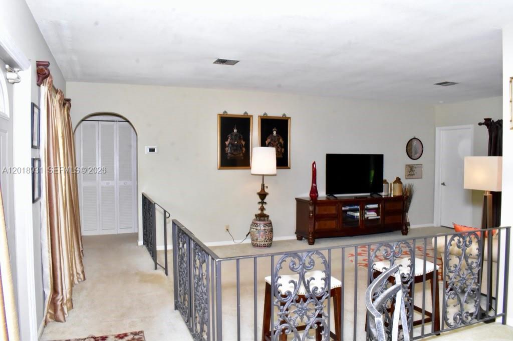 A living room features a metal railing overlooking a lower level and a television console — 3634 Lowson Blvd, Delray Beach FL 33445, DELRAY BEACH, FL