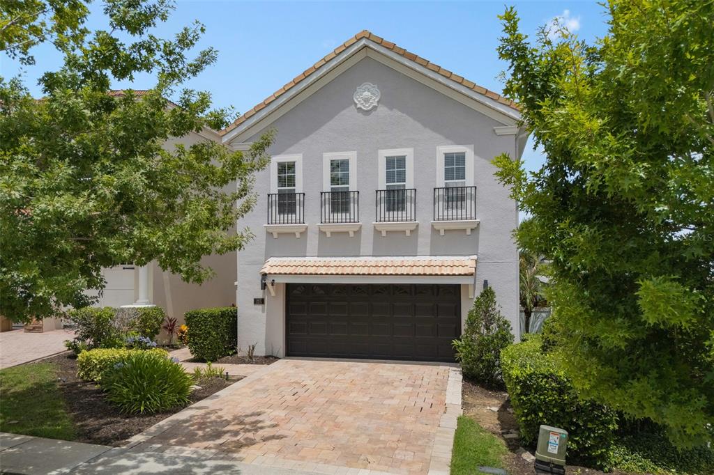 A two-story house with a gray stucco exterior, a brown garage door, and four balconies — 1402 TITIAN COURT, REUNION, FL