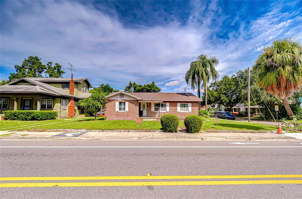 A single-story brick house sits behind a grassy lawn next to a two-story home — 408 E PALM AVENUE, TAMPA, FL