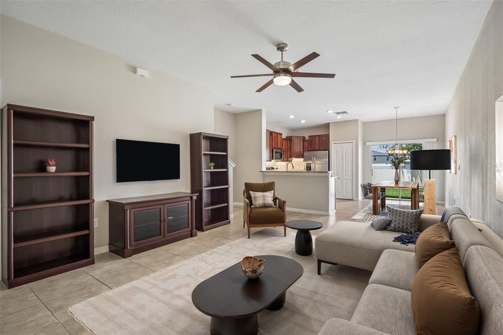 A living room with tile floors, a sectional sofa, a television, and an open kitchen — 2246 GOLDEN FALCON DRIVE, RUSKIN, FL