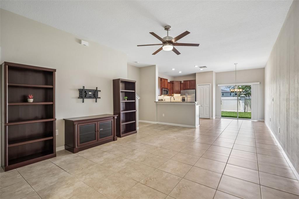An open-concept living and dining area features tile flooring, dark wood furniture, and a kitchen — 2246 GOLDEN FALCON DRIVE, RUSKIN, FL