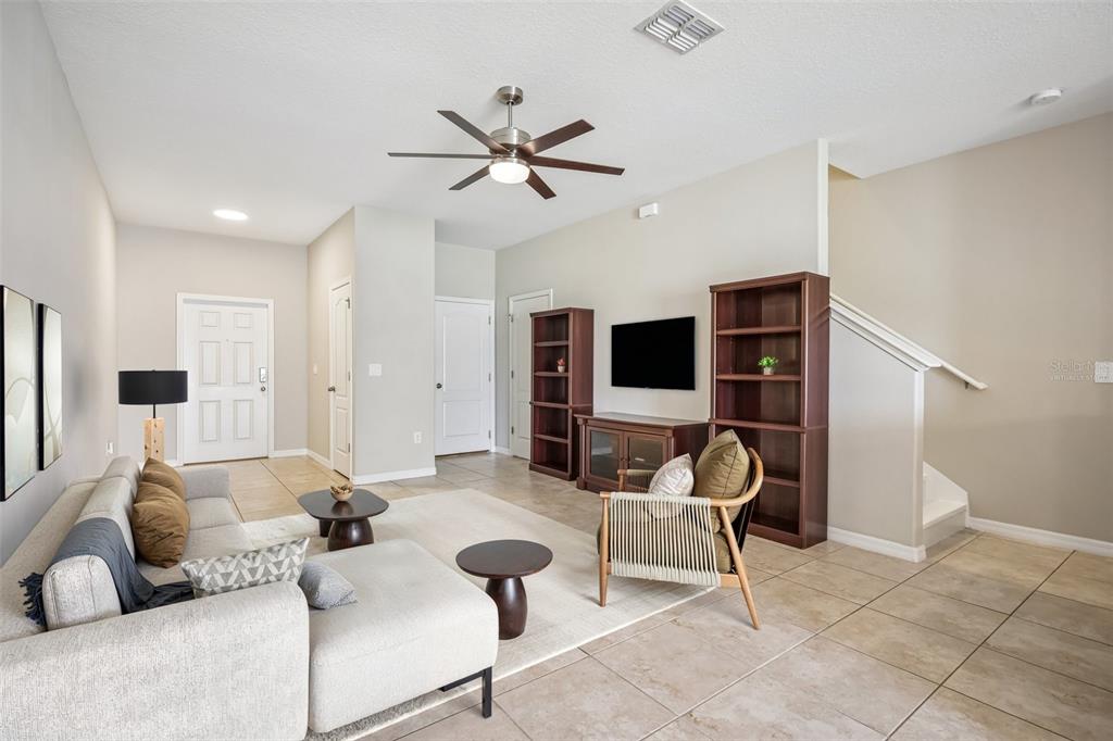 A living room features tile flooring, a ceiling fan, a sectional sofa, and a staircase — 2246 GOLDEN FALCON DRIVE, RUSKIN, FL