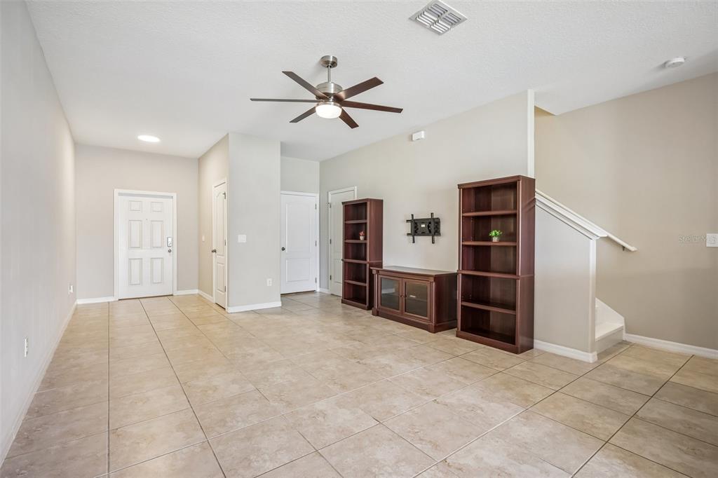 An open living area features tile flooring, a ceiling fan, and dark wood shelving units — 2246 GOLDEN FALCON DRIVE, RUSKIN, FL