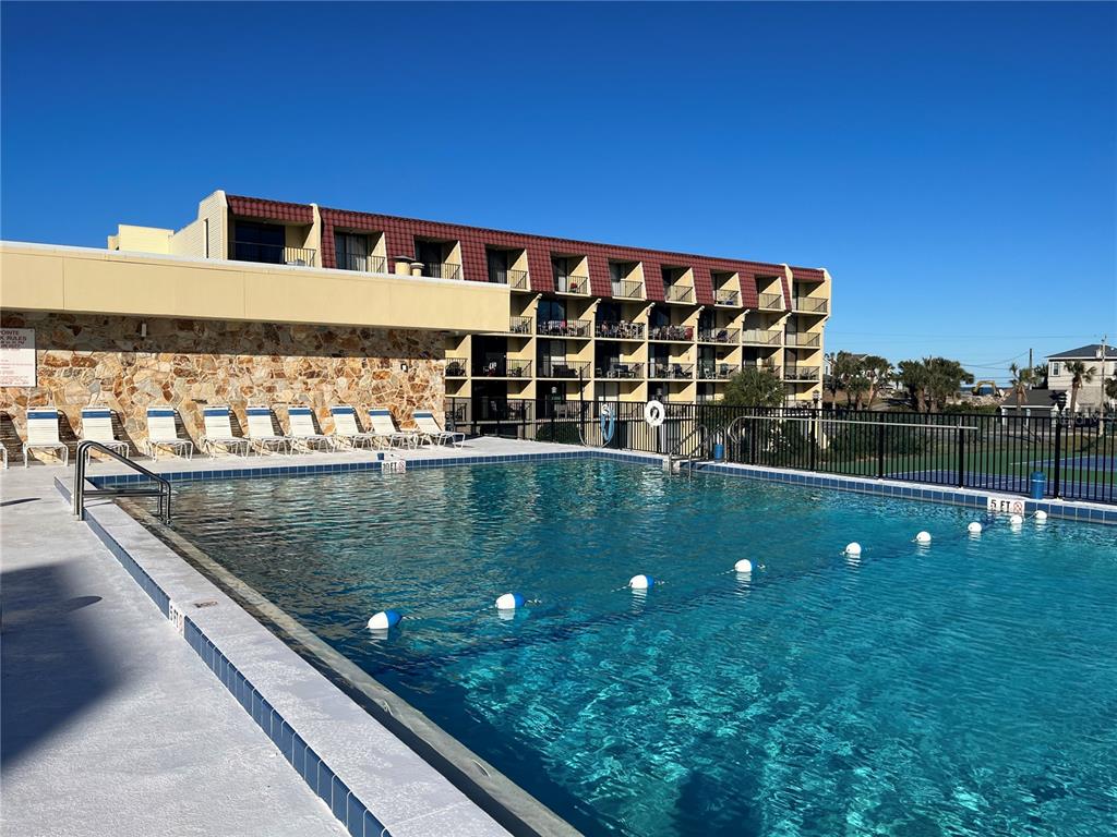 A swimming pool sits in front of a multi-story hotel building with balconies — 1433 N ATLANTIC AVENUE UNIT 223, DAYTONA BEACH, FL