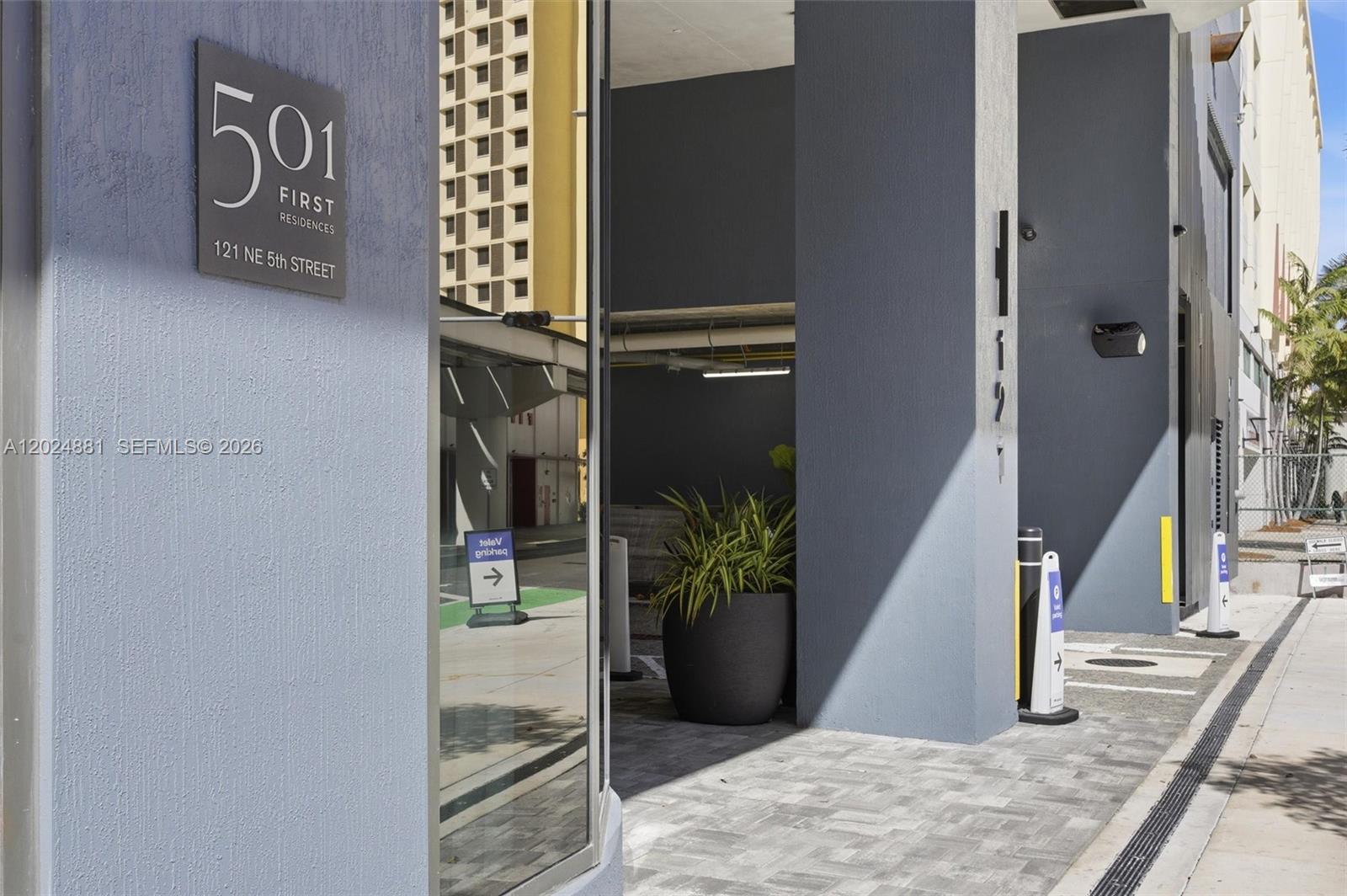 The exterior entrance of a modern building features a sign and a paved walkway — 121 NE 5th St # 1712, Miami FL 33132, MIAMI, FL