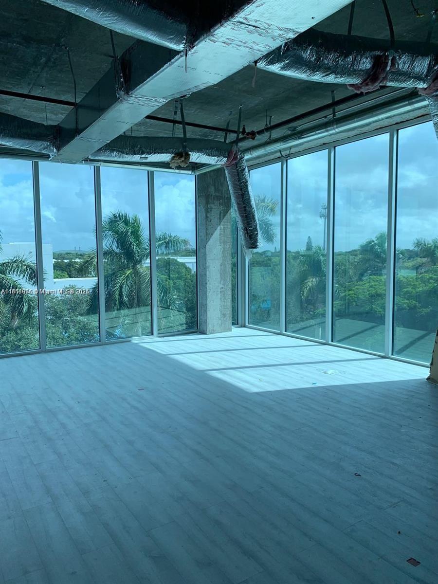 An unfinished room features floor-to-ceiling windows, exposed ceiling ducts, and light-colored wood-look flooring — 10450 NW 33rd St # 309, Doral FL 33172, DORAL, FL