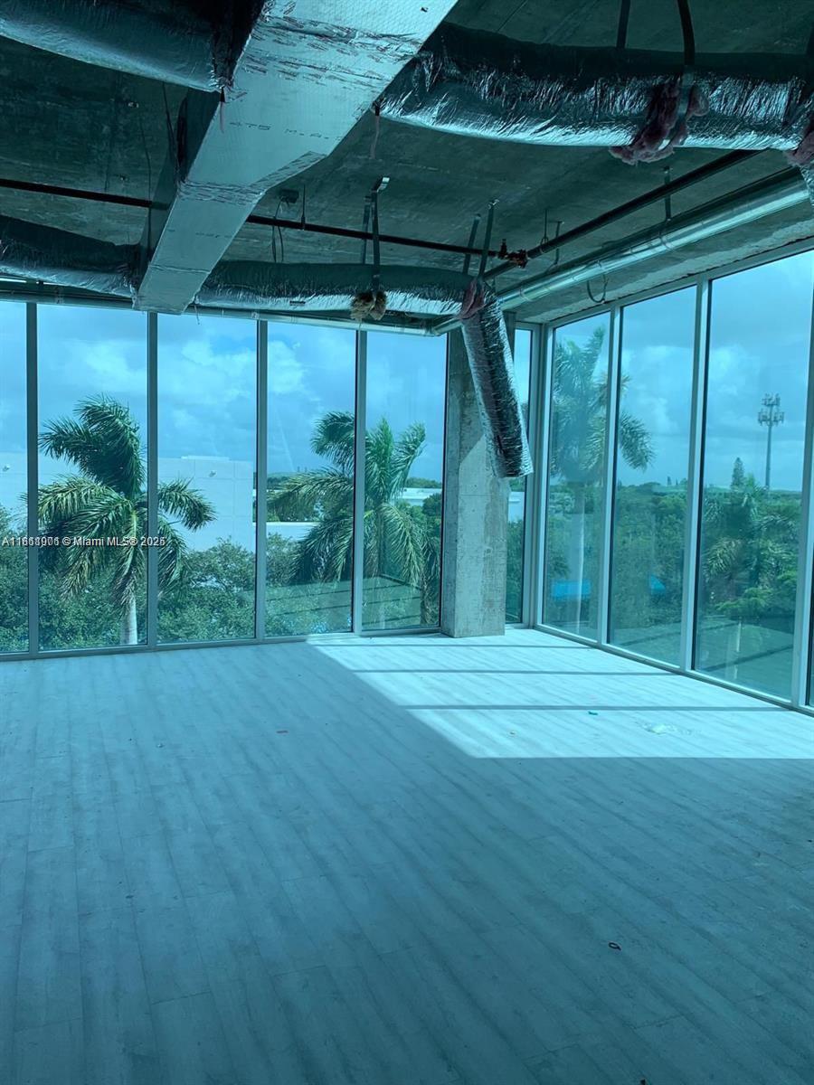 An unfinished room features floor-to-ceiling windows, exposed ceiling pipes, and light-colored wood-look flooring — 10450 NW 33rd St # 309, Doral FL 33172, DORAL, FL