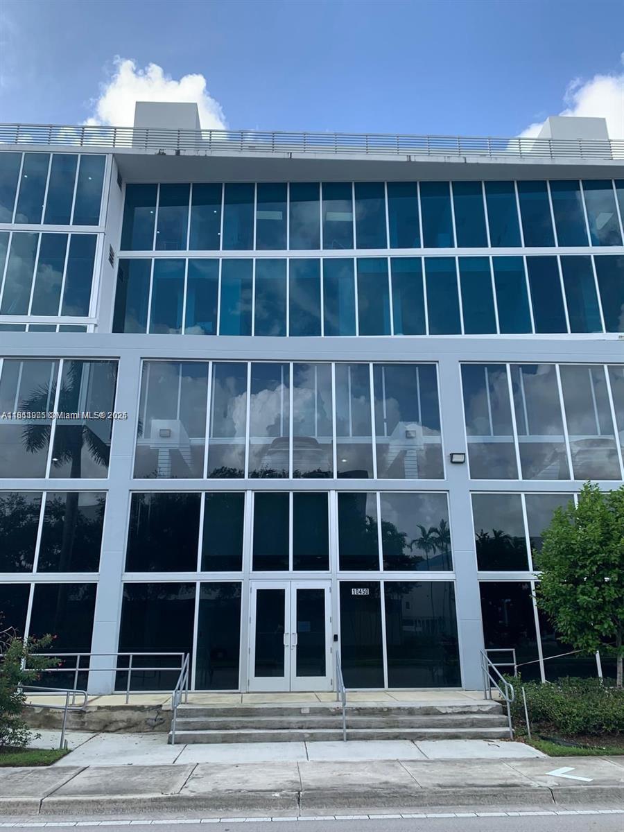 A modern three-story commercial building features a glass facade and a central double-door entrance — 10450 NW 33rd St # 309, Doral FL 33172, DORAL, FL