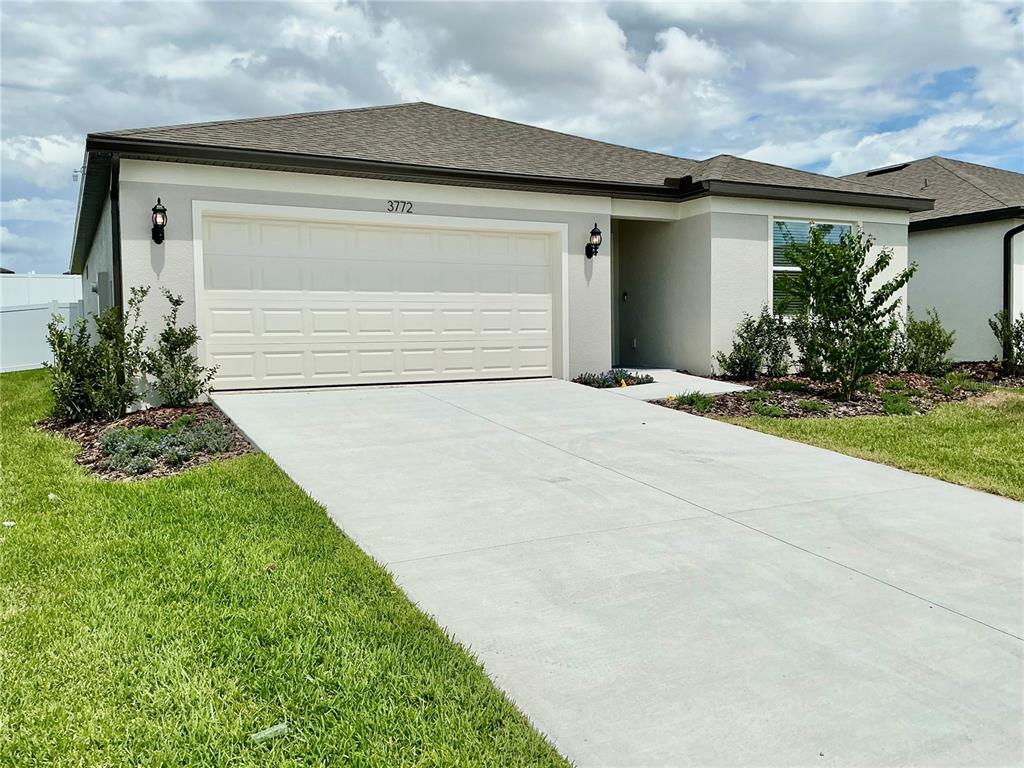 A single-story house with a beige stucco exterior, a two-car garage, and a concrete driveway — 3772 BENHAM RISE ROAD, SPRING HILL, FL