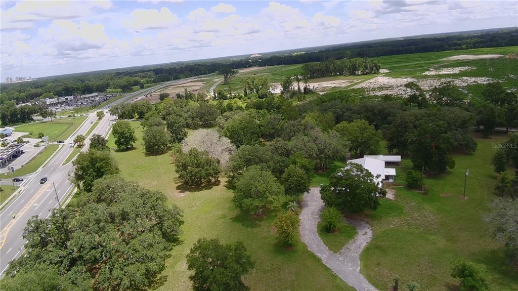 An aerial view shows a house with a white roof surrounded by trees and grass — 24206 DOC KARELAS DRIVE, NEWBERRY, FL