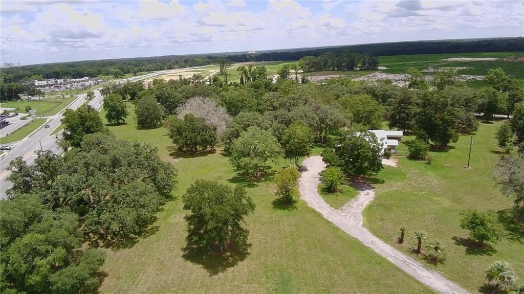 An aerial view shows a house surrounded by trees and a long driveway near a road — 24206 DOC KARELAS DRIVE, NEWBERRY, FL